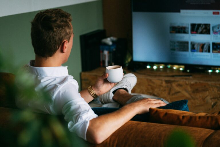 man in white dress shirt holding white ceramic mug watching a vizio TV