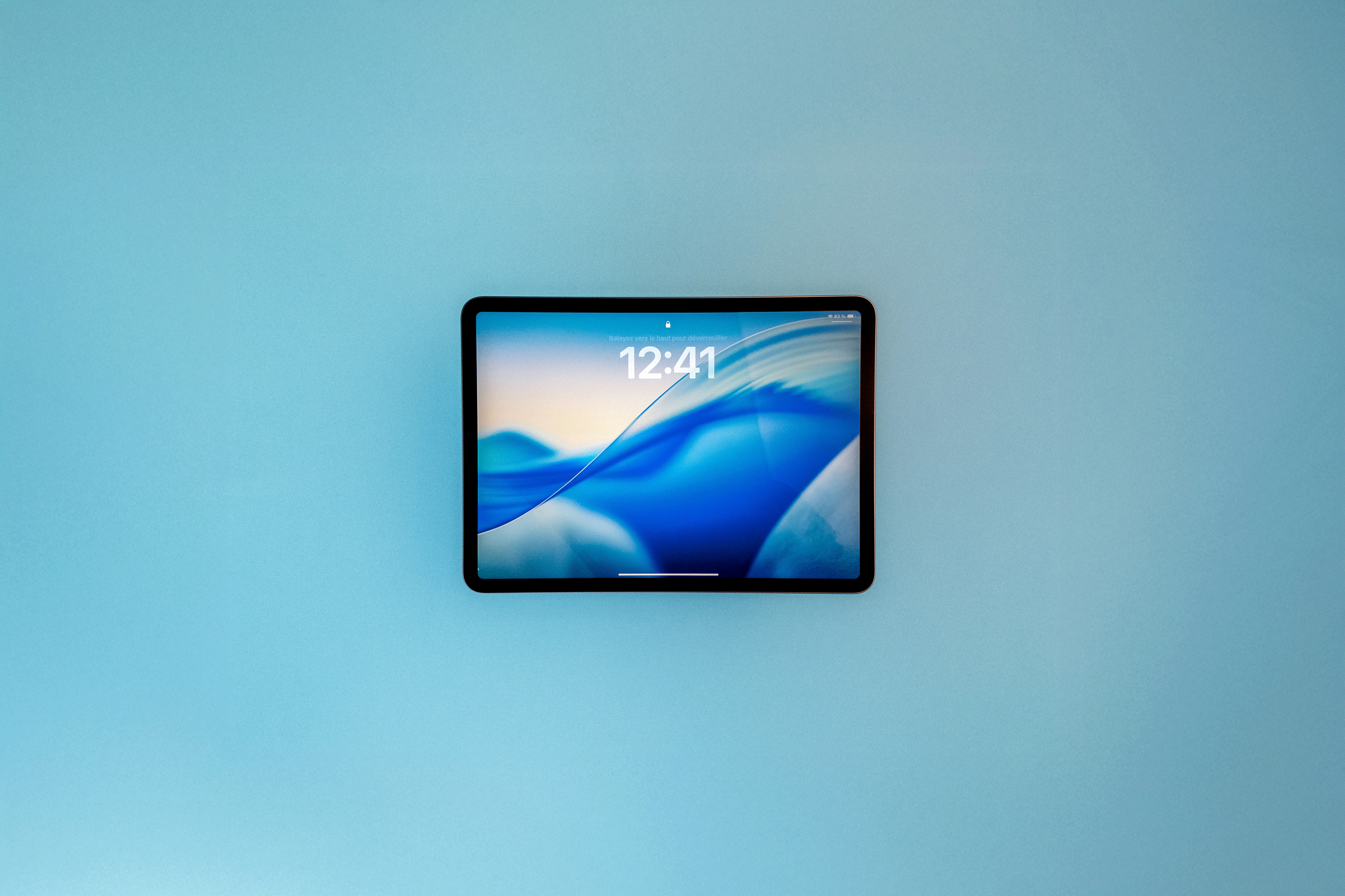 IPad Pro 11 - iOS 26 by TV Brands A tablet displaying a blue abstract wallpaper.
