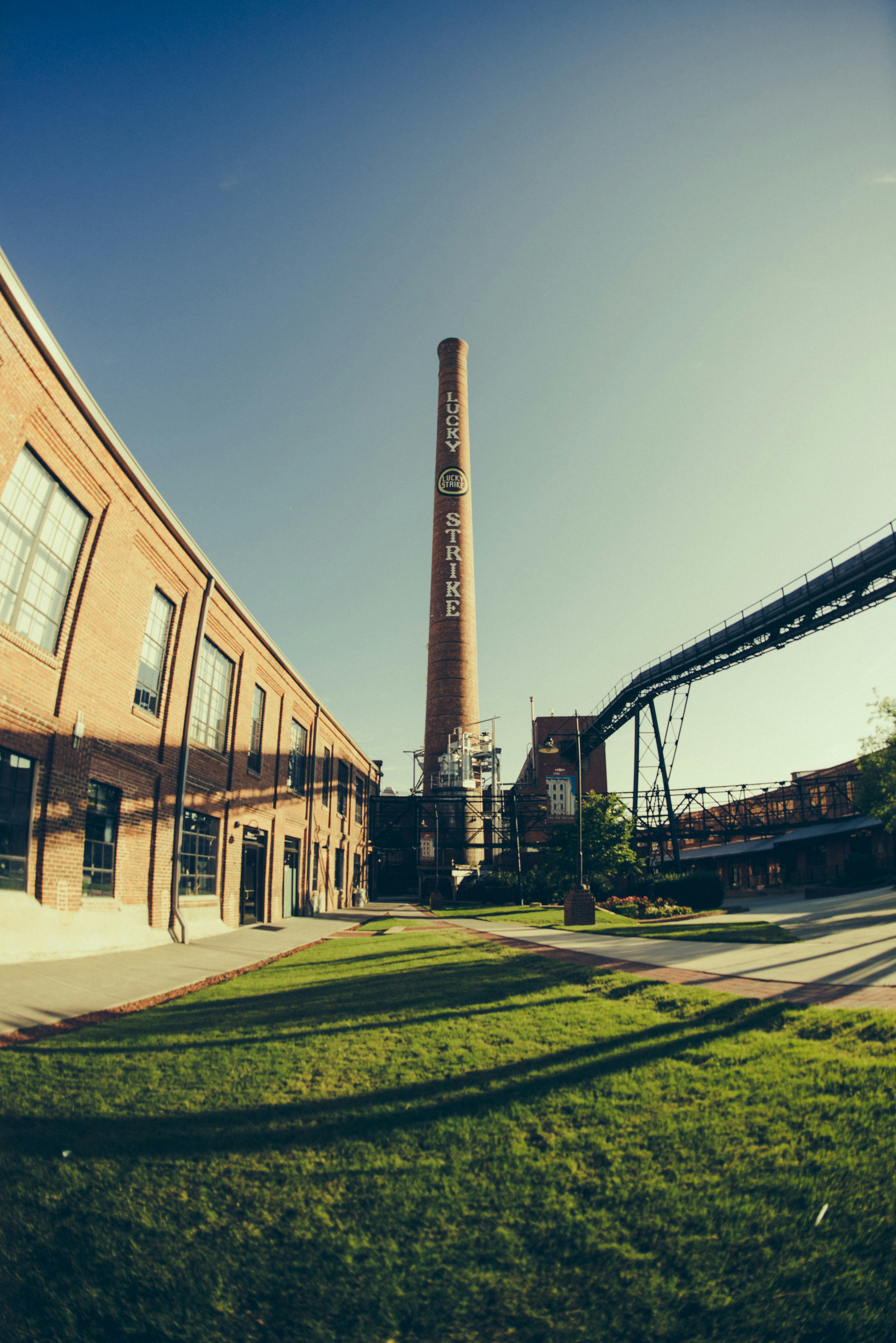 a tall brick building sitting next to a lush green field