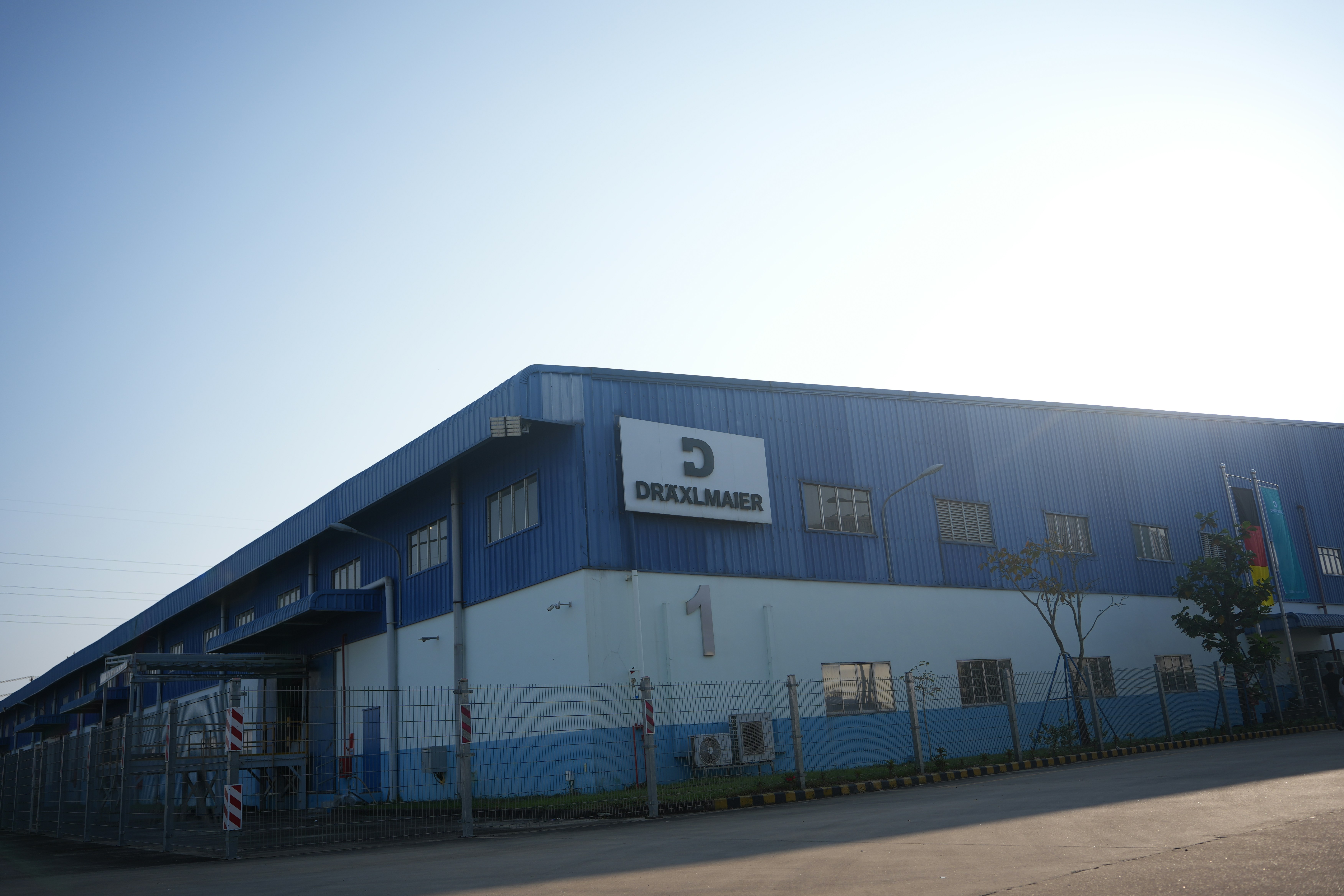 Blue industrial building with company logo under clear sky