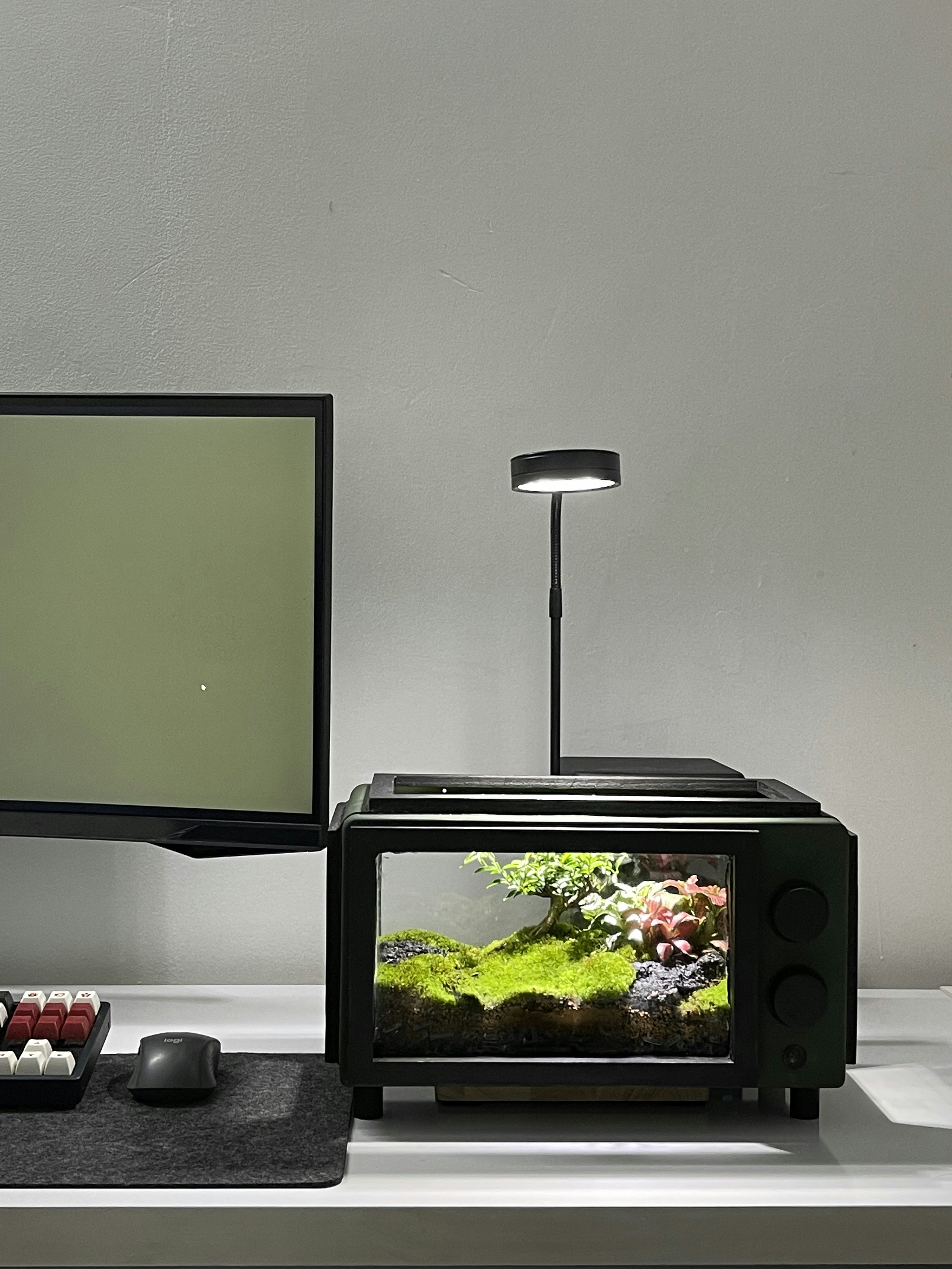 a desk with a monitor, keyboard, mouse and a fish tank