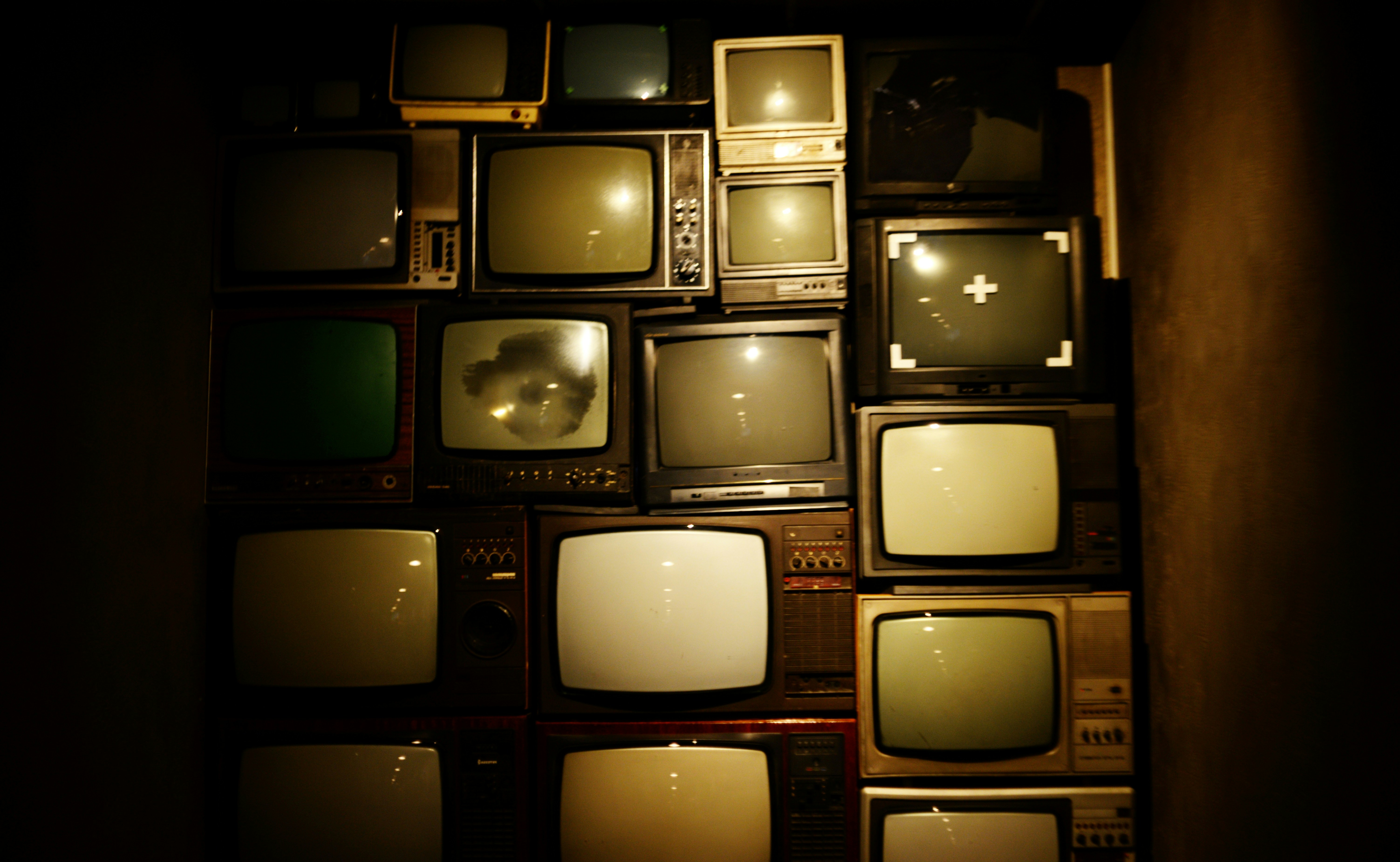 Stack of vintage televisions in dark room