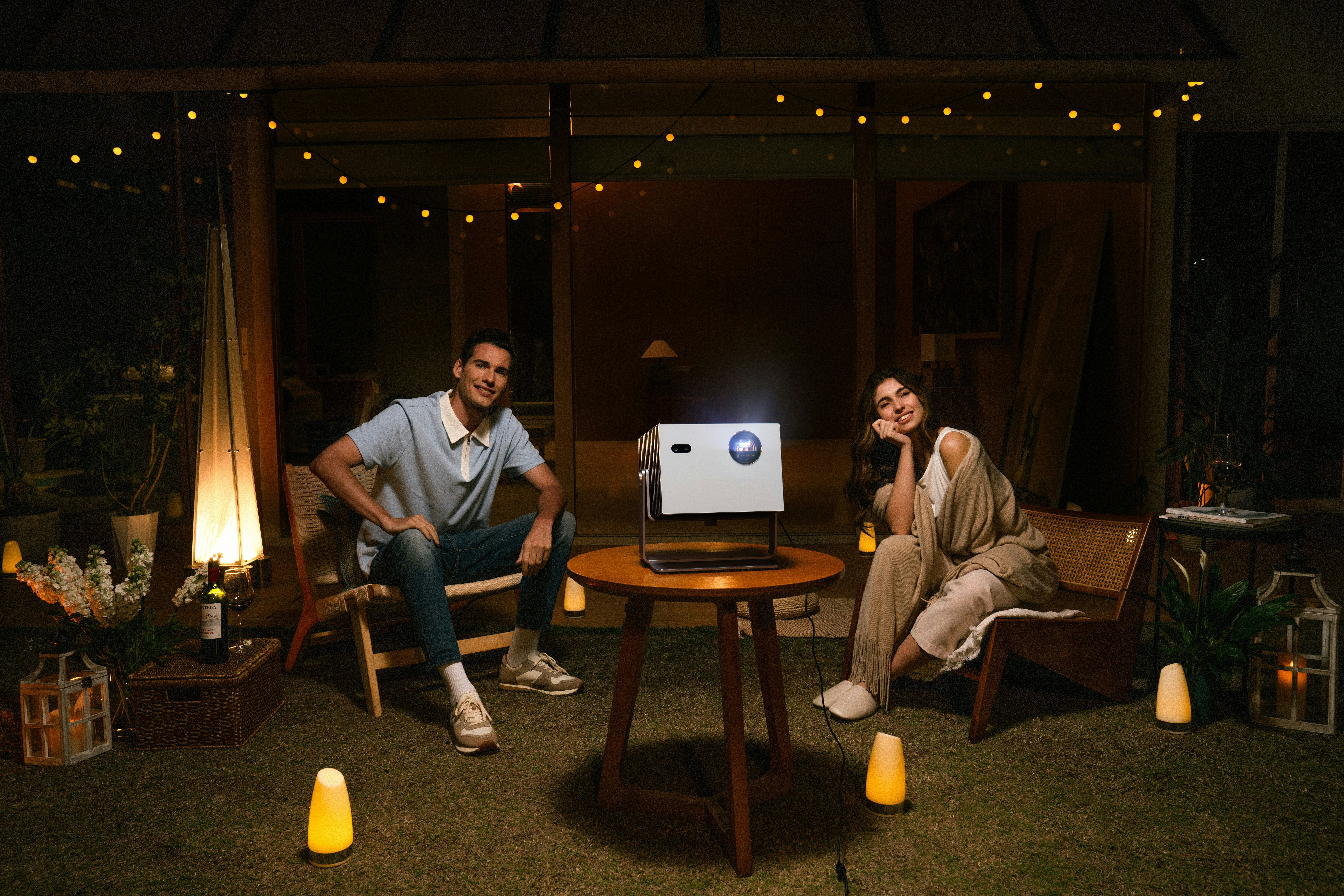 Couple enjoys a movie night with projector outdoors.