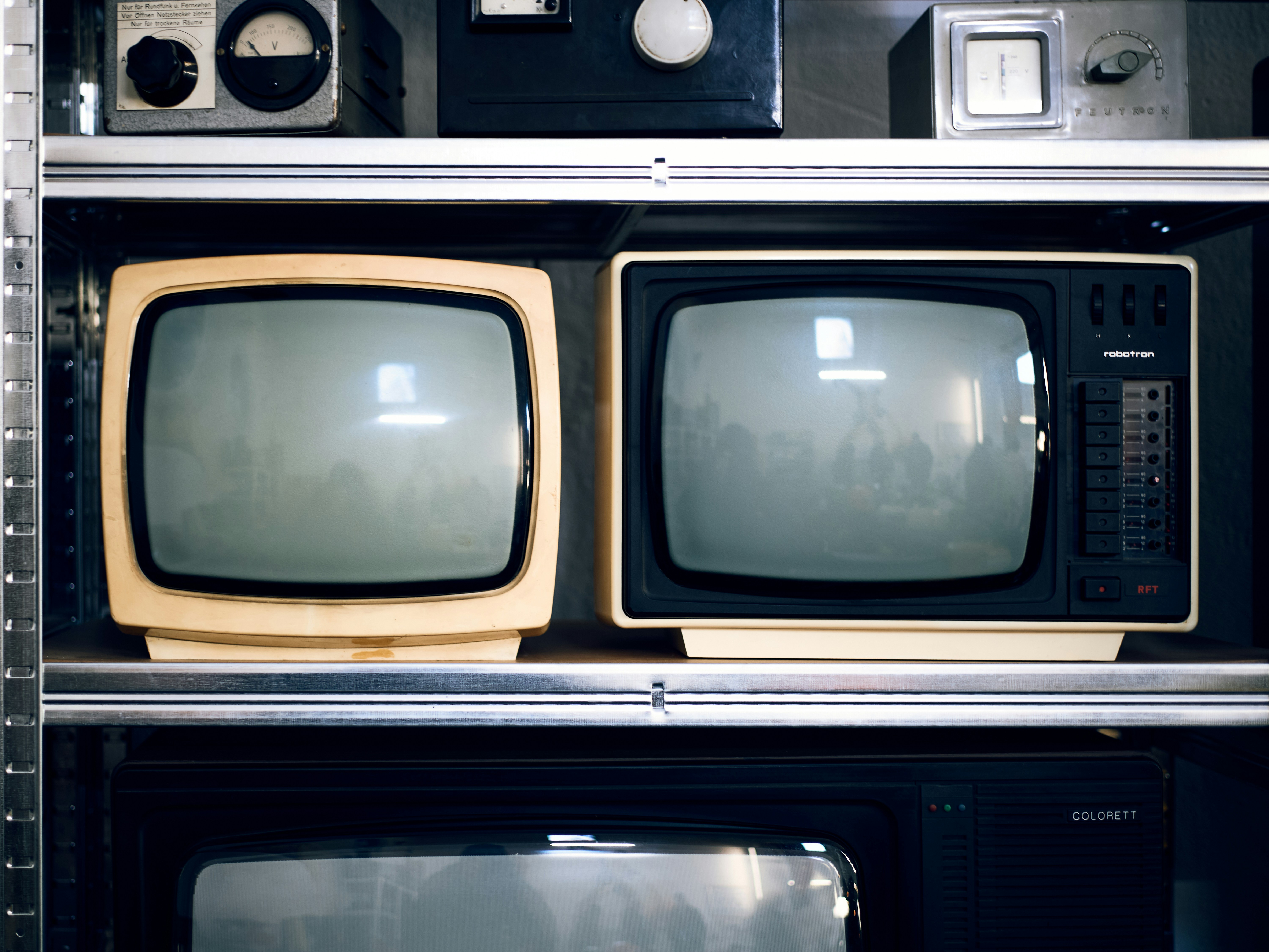 Two vintage televisions on a shelf