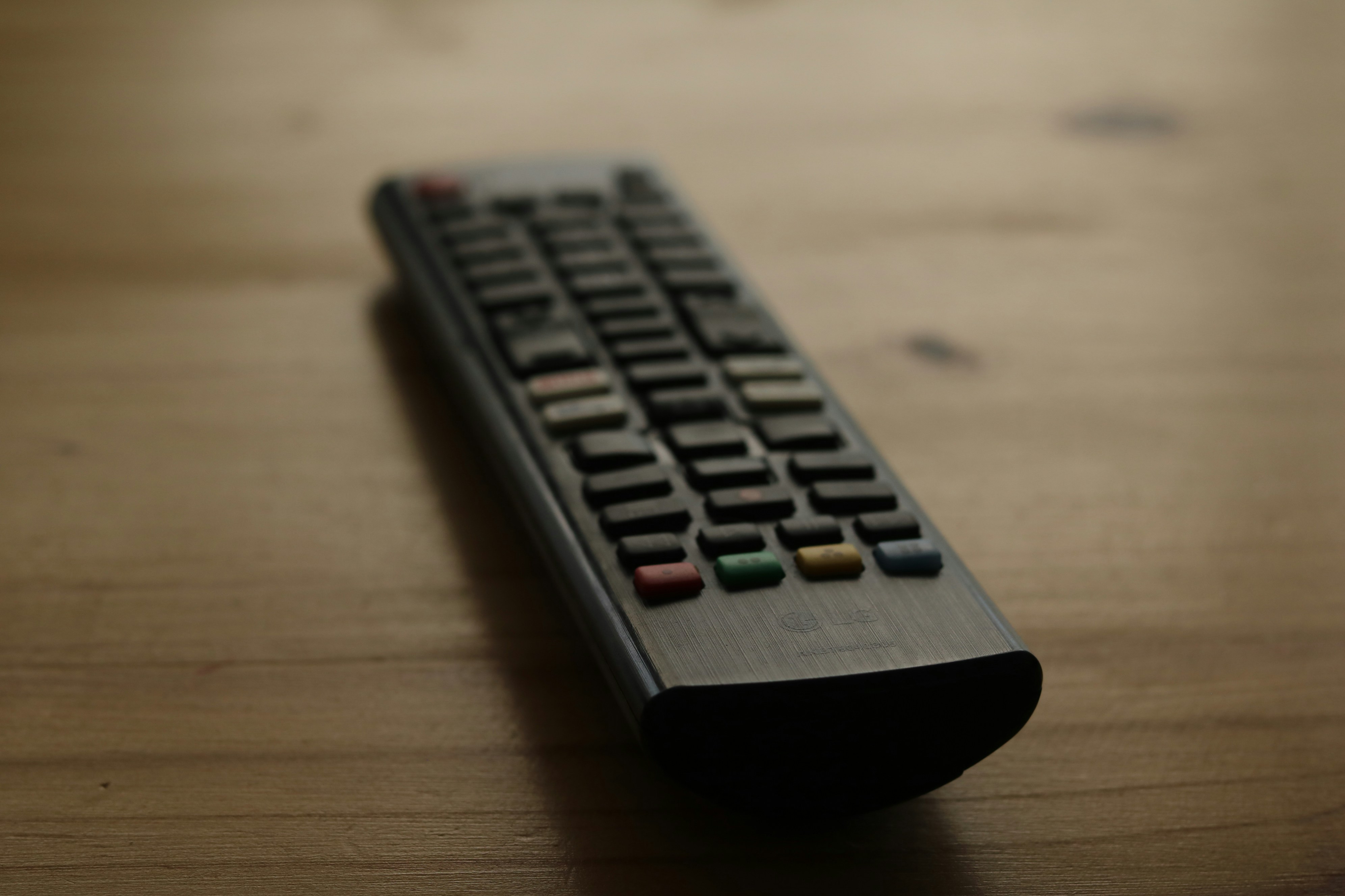Is LG TV good quality? by TV Brands A black remote control rests on a wooden surface.