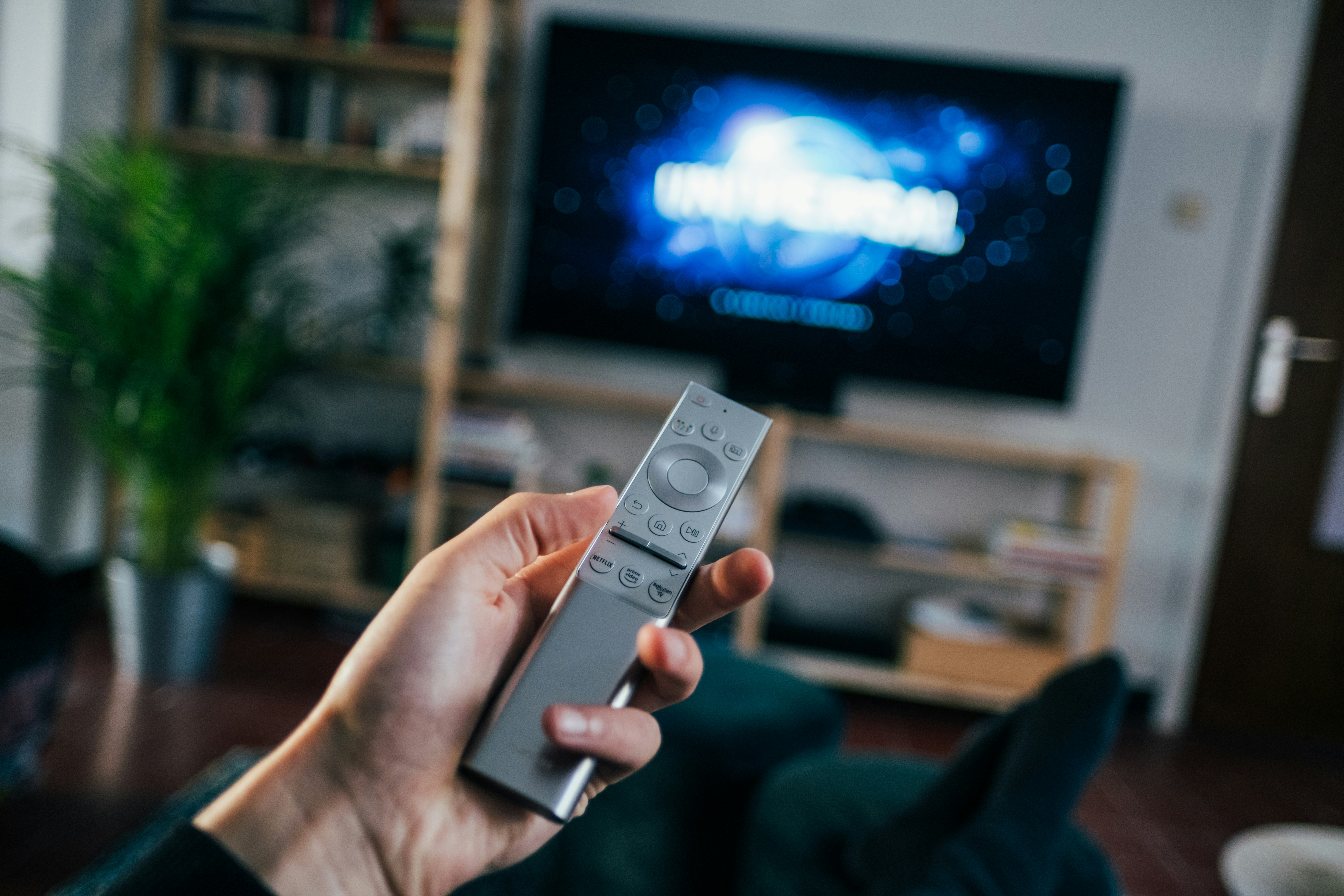 Television on book shelf in living room. Picture taken by Jonas Leupe (www.brandstof.cc/jonas) for Tandem Tech (www.tandemtech.be) by TV Brands person holding gray remote control