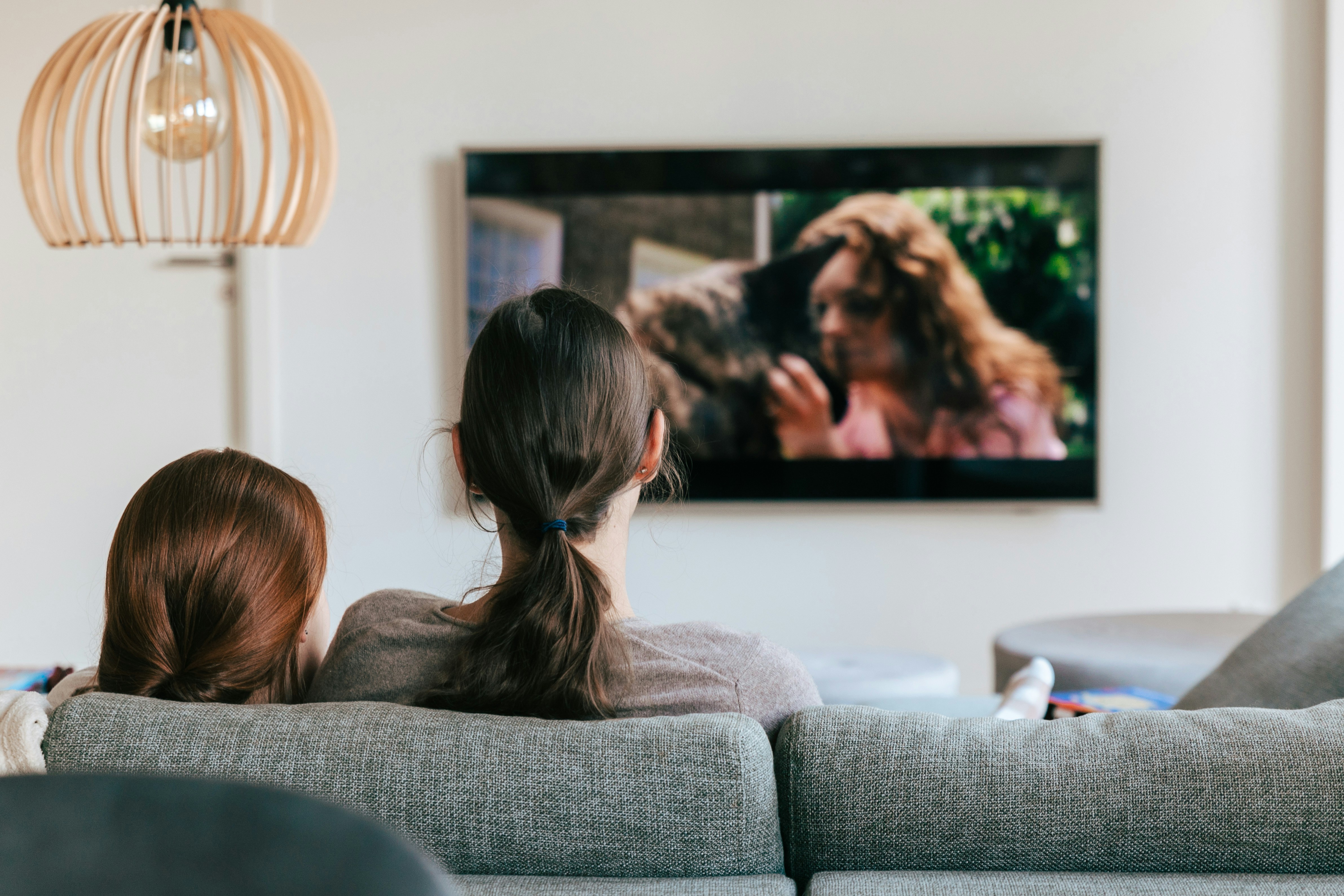 Watching together by TV Brands a couple of women sitting on top of a couch