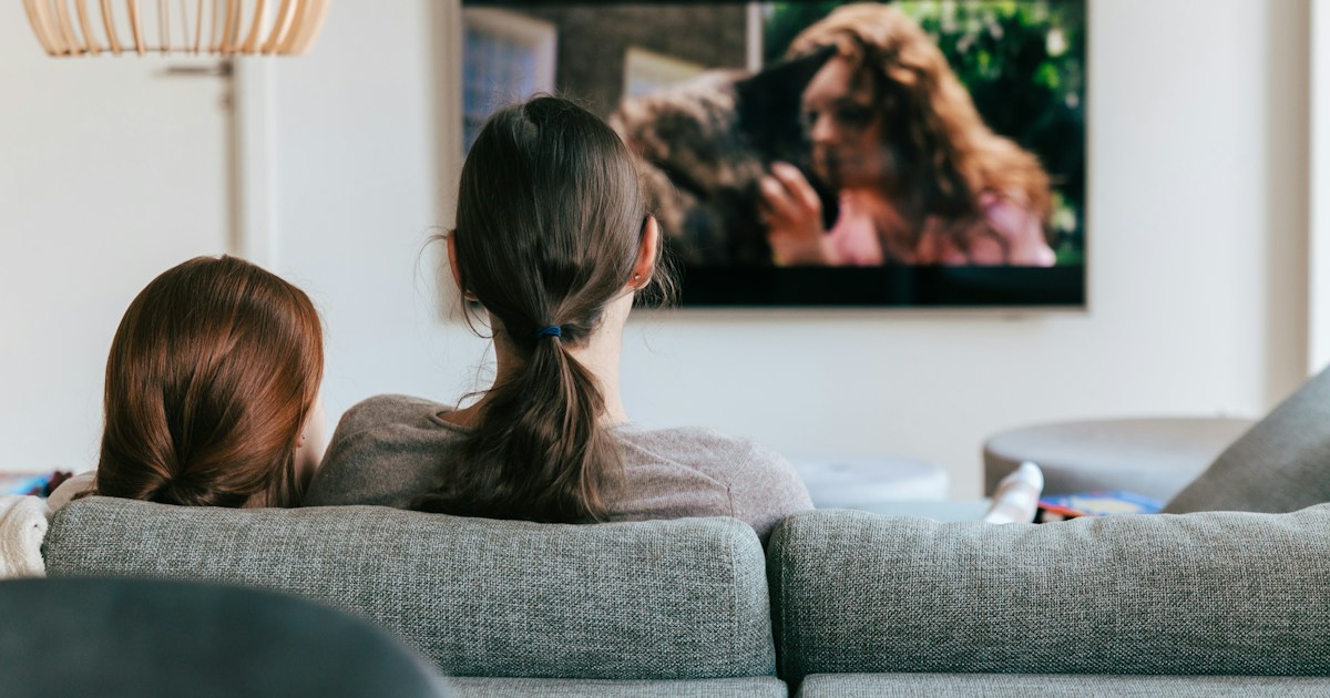 Watching together by TV Brands a couple of women sitting on top of a couch