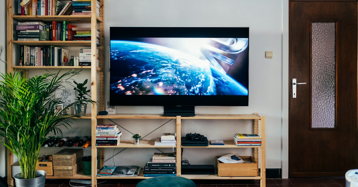 Television on book shelf in living room. Picture taken by Jonas Leupe (www.brandstof.cc/jonas) for Tandem Tech (www.tandemtech.be) by TV Brands black flat screen tv turned on near brown wooden shelf