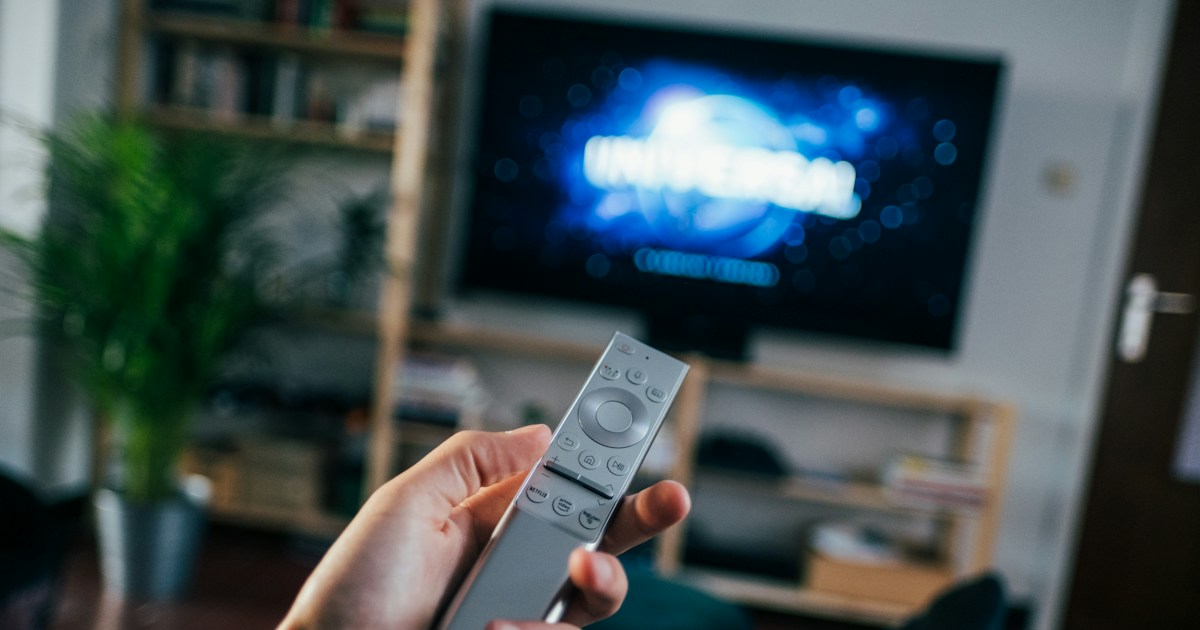 Television on book shelf in living room. Picture taken by Jonas Leupe (www.brandstof.cc/jonas) for Tandem Tech (www.tandemtech.be) by TV Brands person holding gray remote control